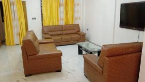 a living room with two couches and a tv at SKY BLUE guest house in Buea