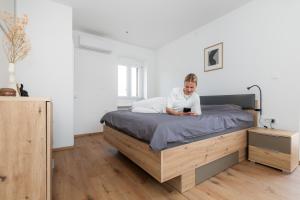 a man sitting on a bed looking at a cell phone at Amare in Mali Lošinj