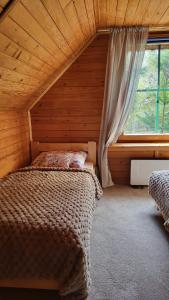 a bed in a wooden room with a window at Forest Sulimówka - dom na wyłączność z dala od sąsiadów in Ruda Kameralna