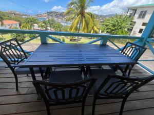 a blue picnic table on a deck with two chairs at CasaCalypso Grenada in Belmont