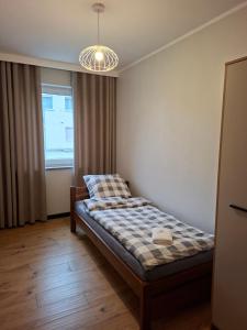 a bedroom with a bed and a window and a chandelier at Apartament 3 - OpolskieNoclegi in Krapkowice