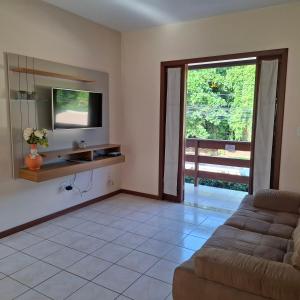 a living room with a couch and a tv at Mestre Lord Apart Hotel 300m Praia Taperapuã by La Vem Férias in Porto Seguro