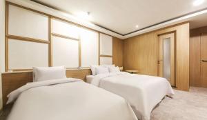 two beds in a room with white sheets at 월호텔 in Pyeongtaek