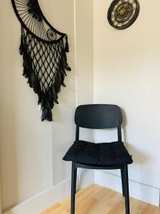 a black chair in a room with a clock at L'Éco'Logis - Meublé de tourisme classé 3 étoiles in Montargis