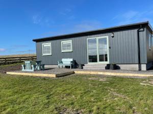 a gray house with a picnic table and a bench at The Glen Lodges, Muriel Cabin in Auckingill