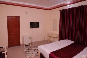 a bedroom with a bed and a desk and a television at Sehrai Royal Villa in Multan +21 photos