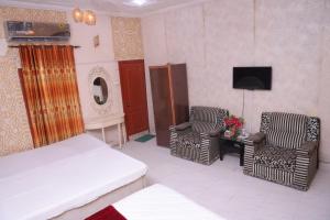 a bedroom with a bed and two chairs and a tv at Sehrai Royal Villa in Multan