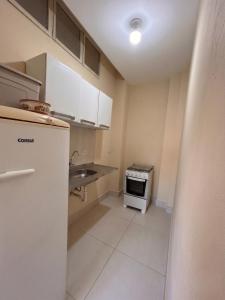 a small kitchen with a refrigerator and a sink at Pousada Mais Cacau in Itu