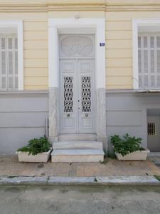 a white door on a house with two potted plants at comfortable room and shared kitchen and bathroom in Athens