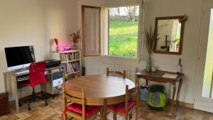 a room with a table and a desk and a window at L'Ombre du pommier in Paron +3 photos