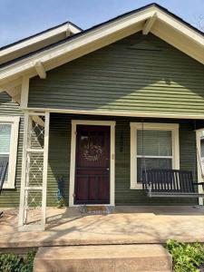 a green house with a red door and a bench at The Gates House in Brady +25 photos