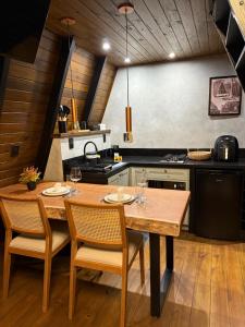 a kitchen with a wooden table with chairs and a stove at Cabanas Girassol in Venda Nova do Imigrante