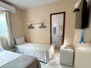 a hotel room with two beds and a bathroom at Casa do Anjo in Fernando de Noronha