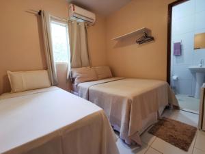 two beds in a room with a window and a sink at Casa do Anjo in Fernando de Noronha