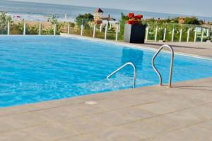 a swimming pool with blue water and the ocean at Luxurious Orchid Apartment in Bijilo