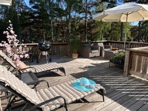 a deck with chairs and an umbrella and a grill at Strömstad/Stromstad close to the sea in Strömstad
