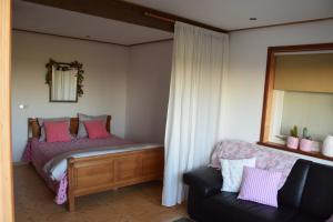 a bedroom with a bed with a mirror and a couch at Maison Zélandaise in Koudekerke