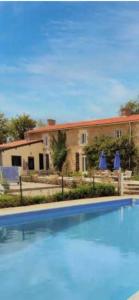 a large swimming pool in front of a house at La Grange aux coccinelles in Saint-Martin-des-Fontaines