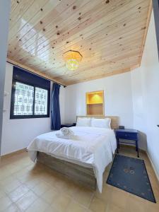 a bedroom with a large bed with a wooden ceiling at Le petit château Vue sur mer Uniquement les familles in Oualidia