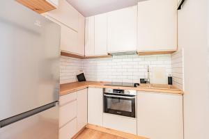 a white kitchen with white cabinets and a stove at Cute house in Kretowiny +3 photos