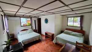 a room with two beds and a table and two windows at Brisa Del Mar in Playa Hermosa