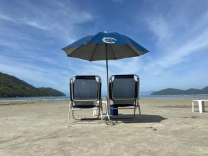two chairs and an umbrella on a beach at Hotel Porto Di Mare in Ubatuba