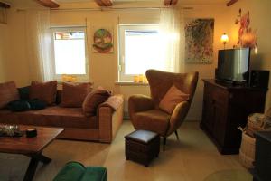 a living room with a couch and a chair and a tv at Ferienwohnung-Brenda in Wolfshagen