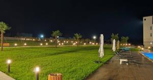 a park with umbrellas and a pool at night at TelaValley Residence in Shalauri