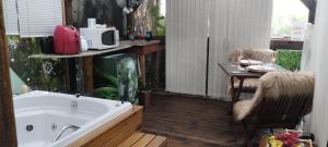a bath tub in a room with a table and a chair at Chalé Hidro Jurerê in Florianópolis +4 photos