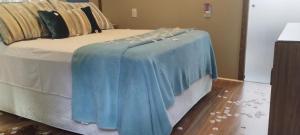 a bed with a blue blanket on top of it at Chalé Hidro Jurerê in Florianópolis