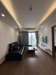a living room with a black leather couch and a large window at BRG Premium Apartments in Hai Phong