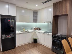 a kitchen with white cabinets and a washer and dryer at BRG Premium Apartments in Hai Phong