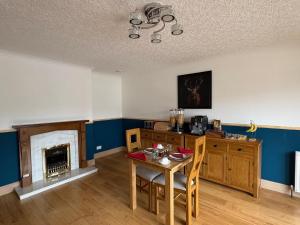 a living room with a table and a fireplace at Kildonan House Bed and Breakfast in Corpach