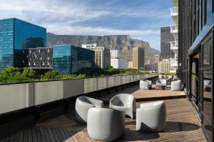 a balcony with white chairs and a view of a city at Crayfish Penthouse - The Onyx Cape Town in Cape Town