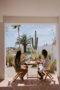 two women sitting at a table on a patio at CasaBlancoMadera in Todos Santos