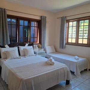 two beds in a room with two windows at Mestre Lord Apart Hotel 300m Praia Taperapuã by La Vem Férias in Porto Seguro +40 photos
