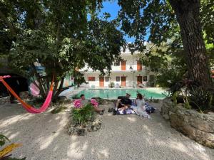 a group of people sitting next to a swimming pool at Casa Mexico Lindo - Boutique Hostel in Bacalar
