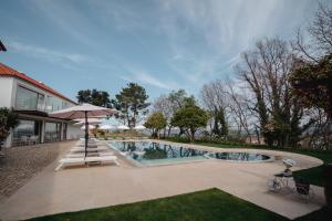 a swimming pool with an umbrella next to a house at Convento do Seixo Boutique Hotel & Spa in Fundão