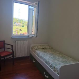 a bedroom with a bed and a chair and a window at ACERO ROSSO in Pianfei