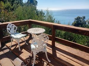 two chairs and a table on a deck with the ocean at Alojha Coliumo Dichato in Coliumo