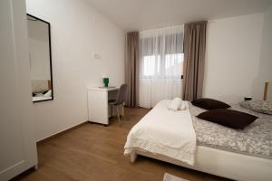 a bedroom with a bed and a desk and a window at Secret Garden Apartman in Varaždin