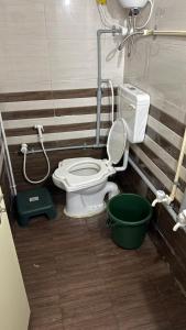 a bathroom with a toilet and a green bucket at Rudraksh Homestay in Dwarka