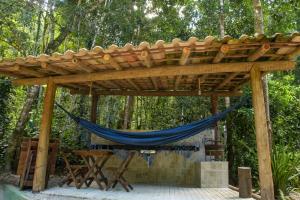 a wooden pergola with a blue hammock under it at Chale 4 com Churrasqueira e Ar a 200m da Praia in Prado