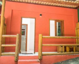 a red building with two windows and a door at Chale 4 com Churrasqueira e Ar a 200m da Praia in Prado