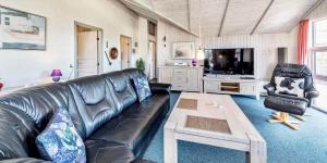 a living room with a leather couch and a tv at VE047-Vejers-Strand-Jafdalvej-91 in Vejers Strand