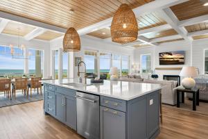 a kitchen with blue cabinets and a living room at Roosevelt Oceanfront Escape by Emerald Isle Realty in Pine Knoll Shores