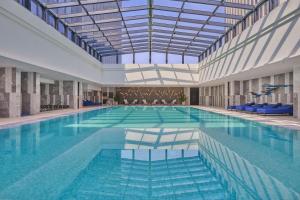 a large swimming pool with blue chairs in a building at Hilton Yancheng in Yancheng