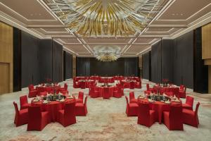 a banquet hall with red tables and chairs and a chandelier at Hilton Yancheng in Yancheng +30 photos