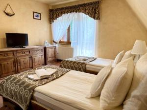 a bedroom with two beds and a tv and a window at Hotel Dwór Karolówka in Zakopane