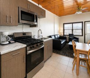 a kitchen with a stove top oven next to a living room at Depe Dene Lakeside Resort in Lake George